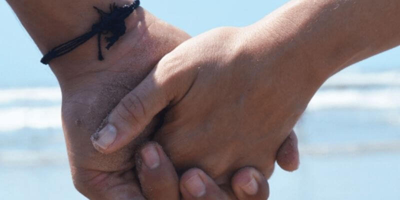 Pareja de la mano en la playa